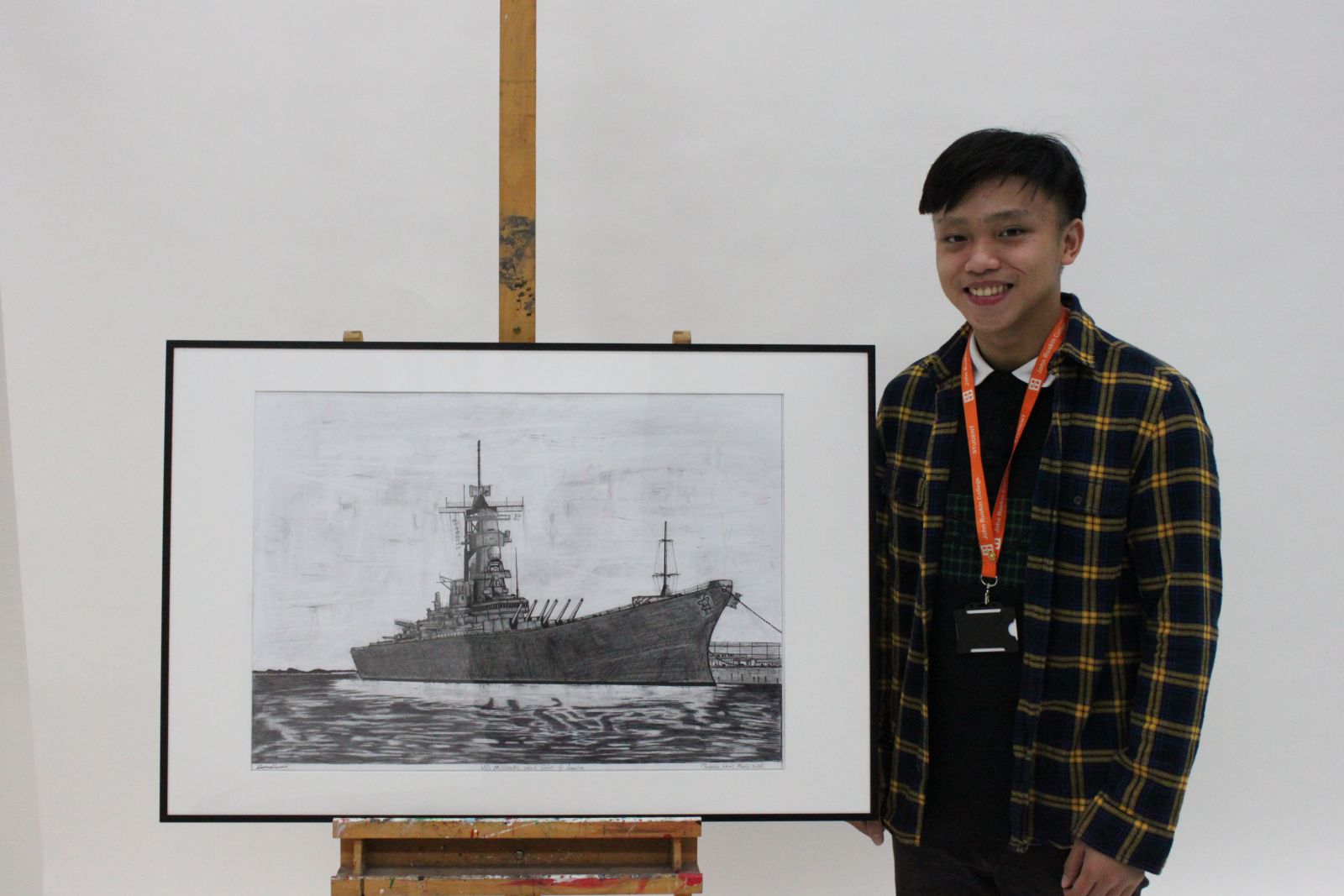 Boy standing next to black and white drawing of a ship on an easel