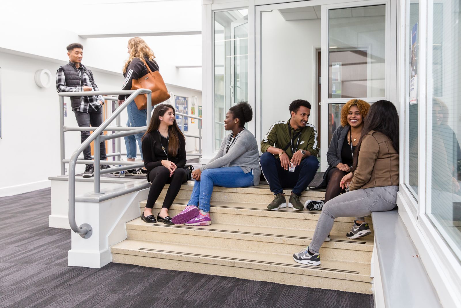 A group of student on some steps indoors, talking