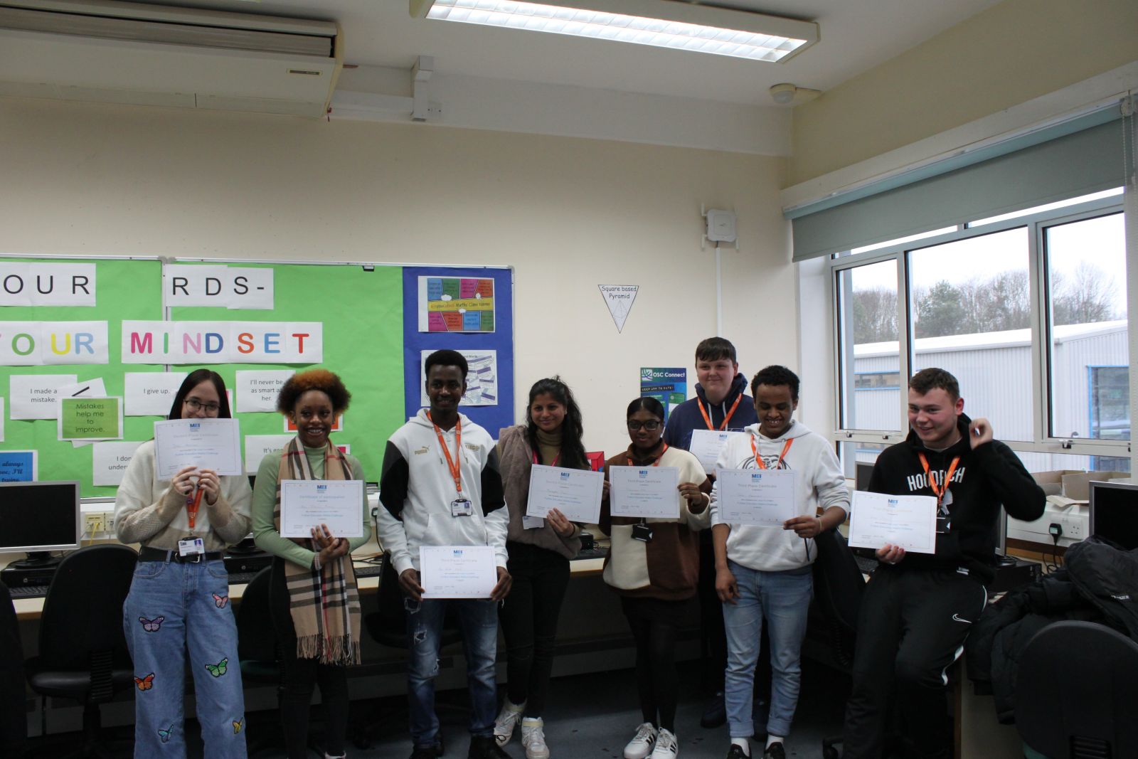Eight students with certificates for achieving 1st, 2nd or 3rd place in the challenge