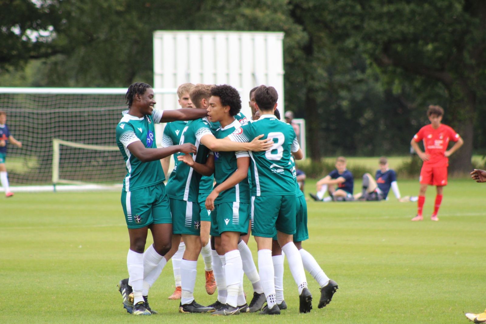 Football players in green shirts congratulating one of their players