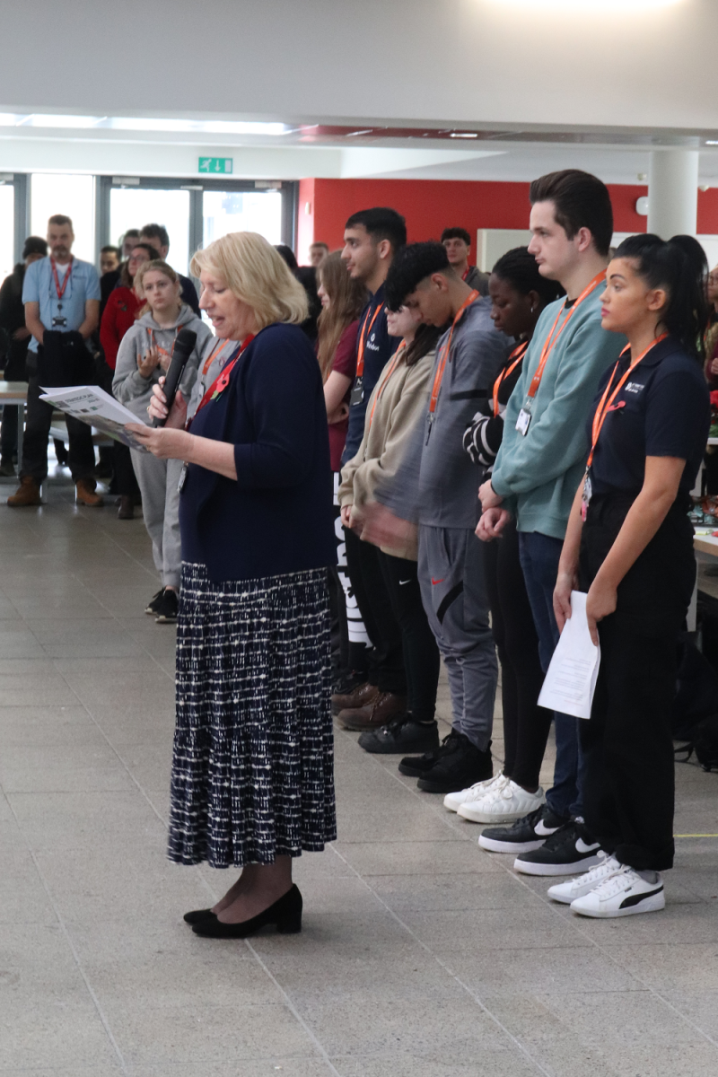 Jayne Dickinson giving a speech with a row of students standing behind her