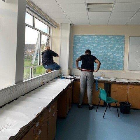 Construction students painting a window